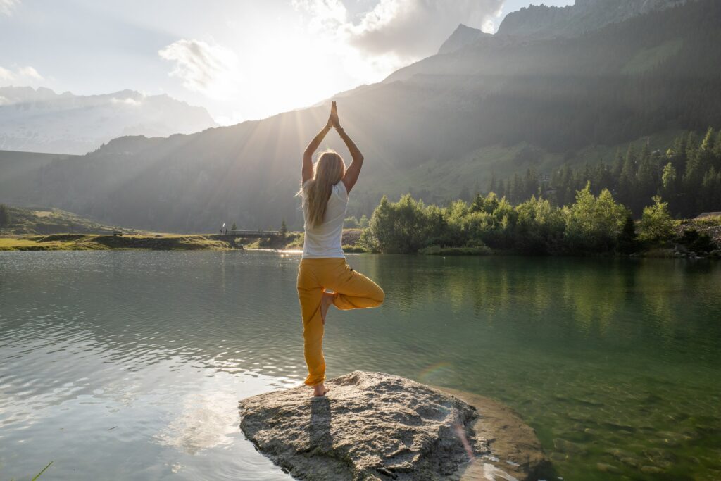 Frau in entspannter Yogahaltung am See