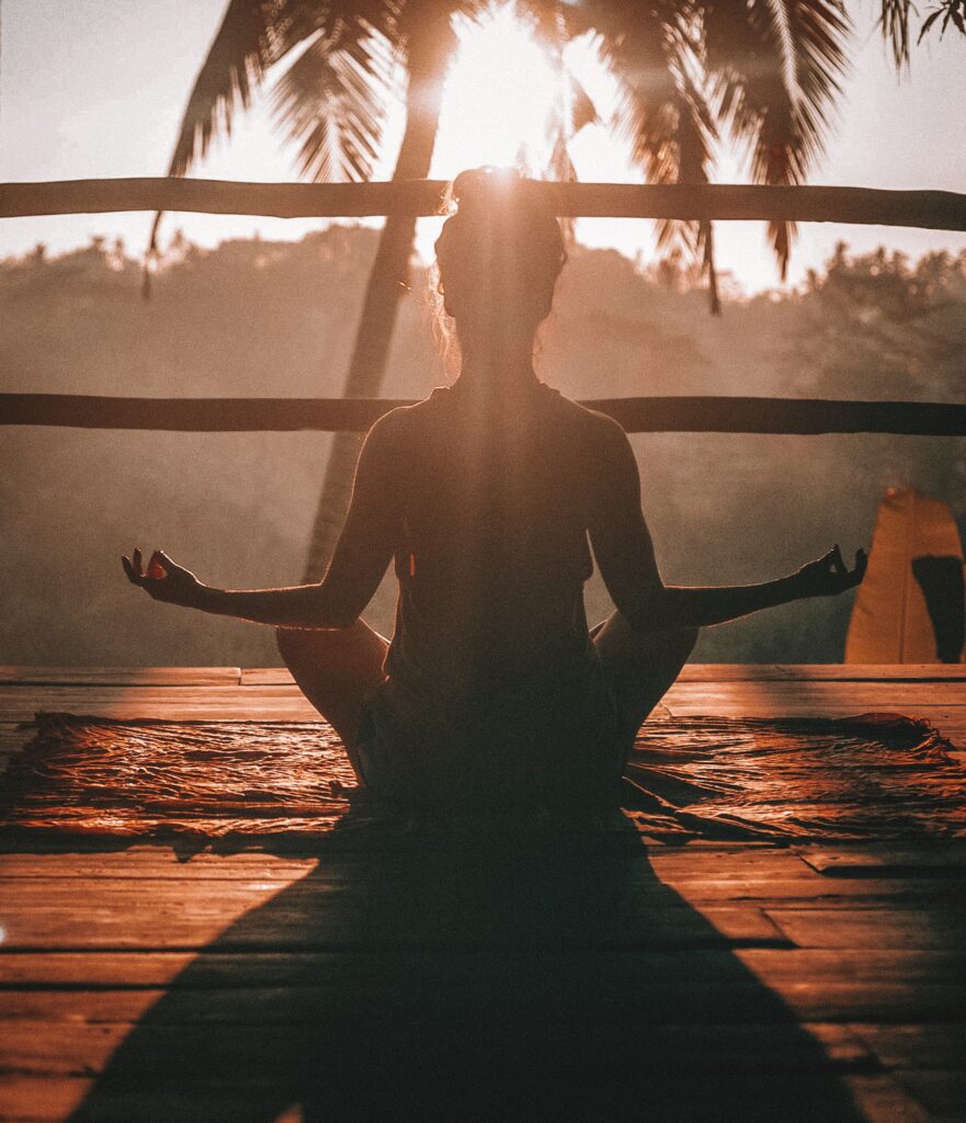 Frau entspannt im Meditationssitz unter Palmen