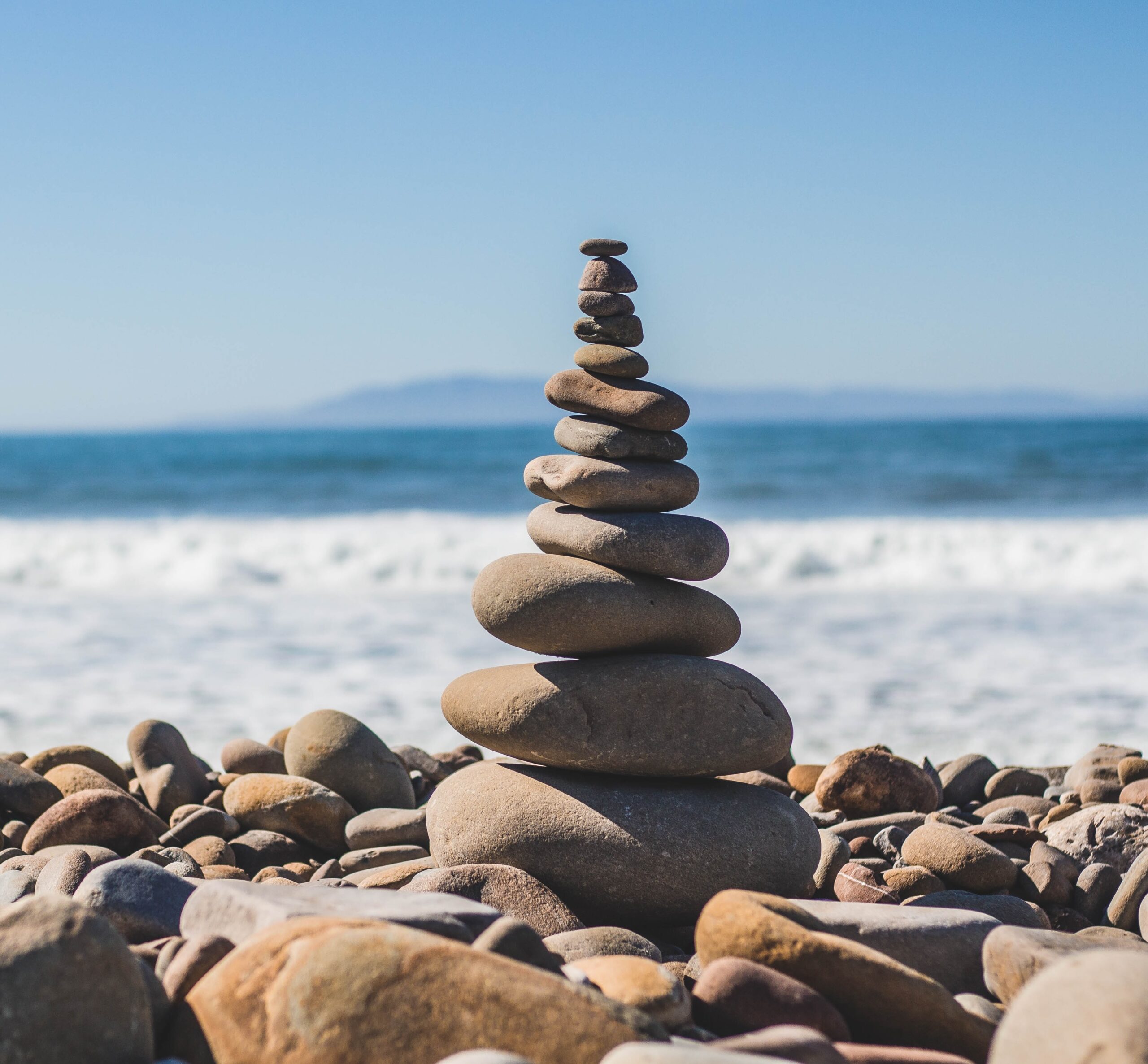Übereinandergestapelte Steine am Strand als Symbol für Life-Balance